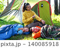 Daughter in sleeping bag, mother sprays repellent, family cares about child's health, camping, prevention from mosquito bites. 140085918