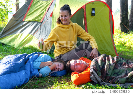 Mother applies repellent, children at tent, bug bite protection, safe leisure, healthy camping, prevention for group outdoors. 140085920