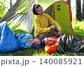 Mother in tent applies bug repellent to children, family health, protection from insect bites, wellness, camping safety, outdoor fun. 140085921