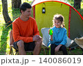 Father and daughter enjoying camping, using mosquito spray, focus on child safety, allergy and disease risk, furniture outdoors, joyful family experience. 140086019
