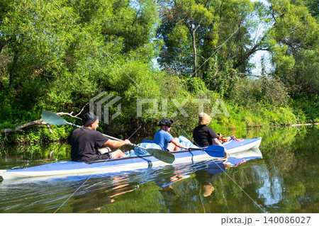 Family paddling the Vuoksa kayak in nature, active summer water trip together, shared teamwork and adventure tourism. 140086027