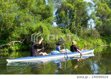 Family in the Varzuga kayak paddling the river, active summer water adventure, teamwork, healthy recreation, leisure for parents and kids. 140086028