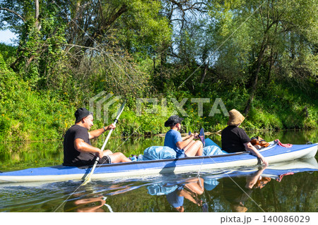 Parents and child paddling the Vuoksa kayak on a calm river, family water trip, teamwork, active summer recreation and healthy leisure. 140086029
