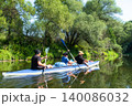 Family kayak trip in the Varzuga inflatable, parents and kids paddling together on the river, active water adventure, teamwork and leisure. 140086032