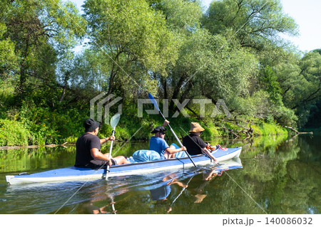 Family kayak trip in the Varzuga inflatable, parents and kids paddling together on the river, active water adventure, teamwork and leisure. 140086032