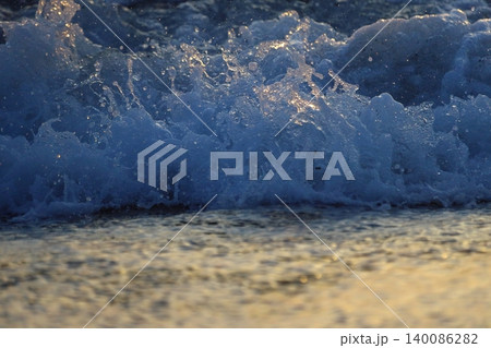Wave splash at sunset close up. Ocean water in sunlight in motion. Abstract sea background Wave splash at sunset close up. Ocean water in sunlight in motion. Abstract sea background 140086282