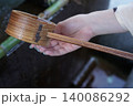 手水舎で柄杓を水で掬う 140086292