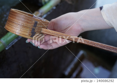 手水舎で柄杓を水で掬う 140086292