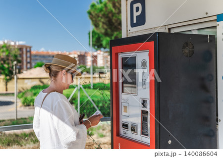 Woman paying at parking meter in coastal resort town Woman paying at parking meter in coastal resort town 140086604