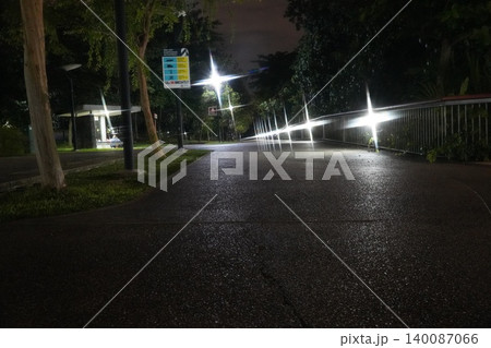 Nighttime park path lit by streetlights dark ambiance Nighttime park path lit by streetlights dark ambiance 140087066