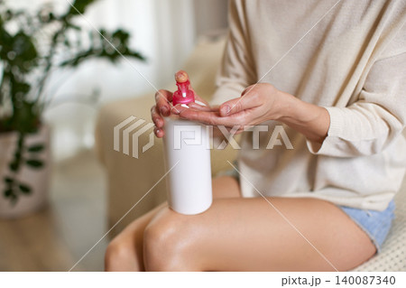 Woman dispensing moisturizing lotion from a pump bottle into her hand, reflecting self-care and beauty ritual Woman dispensing moisturizing lotion from a pump bottle into her hand, reflecting self-care and beauty ritual 140087340