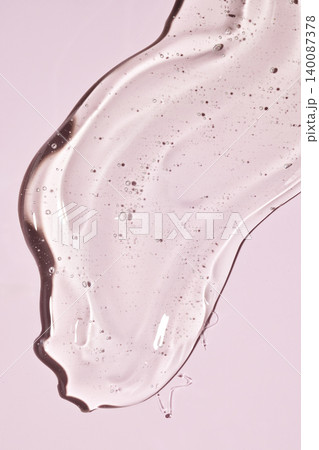 Clear cosmetic gel spreading on pink background Clear cosmetic gel spreading on pink background 140087378