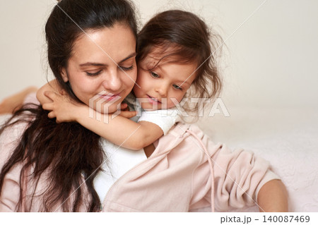 Mother feeling loved as her daughter hugs her from behind, showing strong family connection and tenderness Mother feeling loved as her daughter hugs her from behind, showing strong family connection and tenderness 140087469
