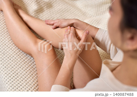 Woman applying self-massage to her knee, finding comfort and addressing muscle tension and discomfort 140087488