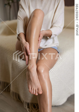 Woman hydrating her body, massaging moisturizer on smooth legs. Concept of skincare, self-care, and beauty routine Woman hydrating her body, massaging moisturizer on smooth legs. Concept of skincare, self-care, and beauty routine 140087490