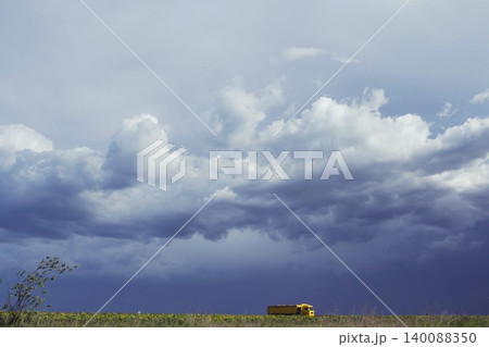 Truck in a field under a dramatic cloudy sky. Large cargo truck on the highway against a beautiful landscape with a cloudy sky. Truck in a field under a dramatic cloudy sky. Large cargo truck on the highway against a beautiful landscape with a cloudy sky. 140088350