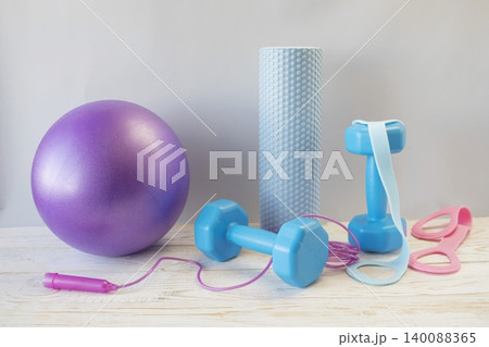 Equipment for yoga and pilates. Yoga blocks, roller, expander and massage ball on a wooden surface. 140088365