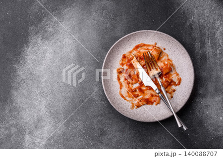 A dirty plate after a meal with leftover pasta and tomato sauce, cleaning. An empty dirty plate A dirty plate after a meal with leftover pasta and tomato sauce, cleaning. An empty dirty plate 140088707