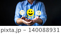 Businessman hands holding yellow happy smile face icon with five star rating. Concept of customer satisfaction survey, excellent service feedback, and positive business review experience. 140088931