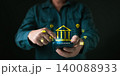 Hands using mobile phone accessing digital banking application with hologram bank building icon. Concept of online financial transaction security and cyber internet payment technology. 140088933