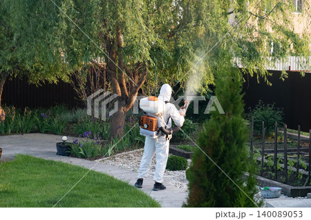 Spring garden pest control: man in protective suit spraying plants Spring garden pest control: man in protective suit spraying plants 140089053