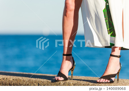 Woman feet in high heels shoes on sea pier Woman feet in high heels shoes on sea pier 140089068
