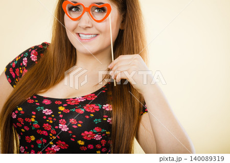Happy woman holding fake eyeglasses on stick 140089319