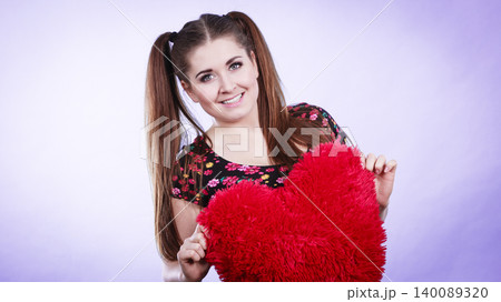 Happy woman holding heart shaped pillow 140089320