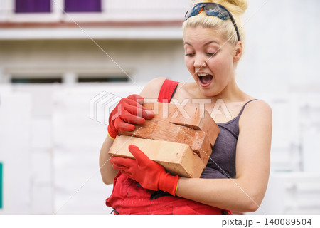 Funny woman carrying heavy bricks 140089504