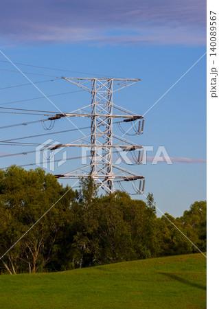 A large electricity transmission tower surrounded by trees on a hill 140089567