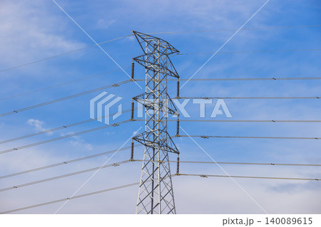 A large electricity transmission tower in front of a vibrant blue sky A large electricity transmission tower in front of a vibrant blue sky 140089615