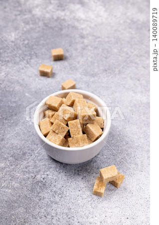 Brown sugar cubes in bowl on gray background Brown sugar cubes in bowl on gray background 140089719