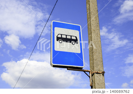 Blue rectangular bus stop sign on an old metal pole. Black silhouette of a bus on a white background symbolizes the passenger boarding area. 140089762