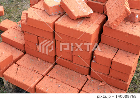 Red ceramic bricks stacked on a wooden pallet at a construction site. High-quality clay building blocks, ready for wall construction, home renovation Red ceramic bricks stacked on a wooden pallet at a construction site. High-quality clay building blocks, ready for wall construction, home renovation 140089769