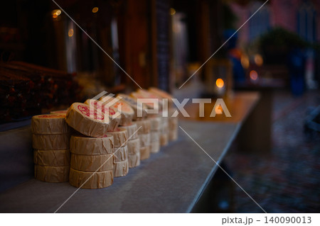 Rows of traditional artisanal cheese wheels wrapped in paper Rows of traditional artisanal cheese wheels wrapped in paper 140090013