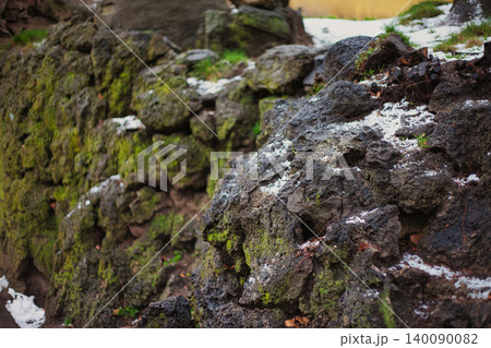Textured Lava Rock Formation Covered in Green Moss and Light Snow Textured Lava Rock Formation Covered in Green Moss and Light Snow 140090082