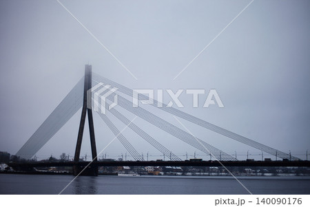 Cabled-stayed bridge over a wide river on a misty day 140090176