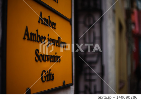 Close-up of a rustic, angled yellow metal sign with raised black letters listing Close-up of a rustic, angled yellow metal sign with raised black letters listing 140090286