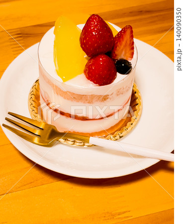 白いお皿に載ったイチゴと桃のミニケーキとゴールドのフォーク 白いお皿に載ったイチゴと桃のミニケーキとゴールドのフォーク 140090350