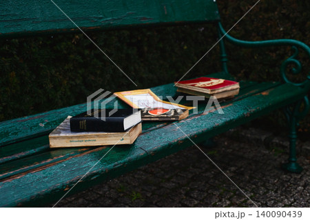 Old books left on a green wooden bench in a park Old books left on a green wooden bench in a park 140090439