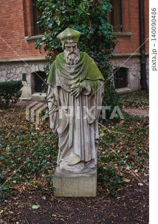 Ancient stone statue of a bearded cleric in a historic courty 140090486