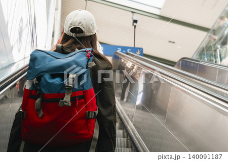 Young woman with a backpack on an escalator at a railway station, highlighting modern travel and transit infrastructure. Young woman with a backpack on an escalator at a railway station, highlighting modern travel and transit infrastructure. 140091187