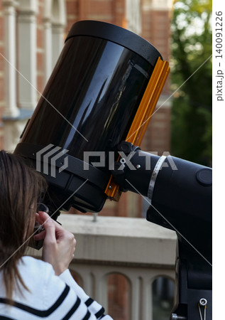 Person observing the sky through a telescope, illustrating science education and hands on learning tools for exploring the sky. 140091226