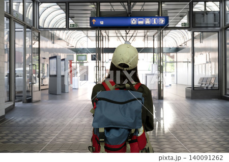 Young woman with a backpack looking at a blue overhead information sign at the railway station, illustrating passenger navigation. Young woman with a backpack looking at a blue overhead information sign at the railway station, illustrating passenger navigation. 140091262