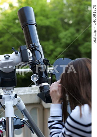Astronomy enthusiast observing sky using telescope, showing hands on use of astronomical instruments for hobbyists. 140091279