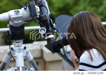 Person looking through an astronomical telescope eyepiece in a close up view, demonstrating amateur astronomy equipment in use. Person looking through an astronomical telescope eyepiece in a close up view, demonstrating amateur astronomy equipment in use. 140091299