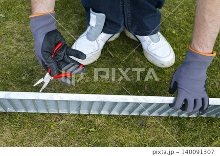 A person wearing gloves holds a pliers during a drain grate maintenance, focusing on proper safety gear and careful handling A person wearing gloves holds a pliers during a drain grate maintenance, focusing on proper safety gear and careful handling 140091307