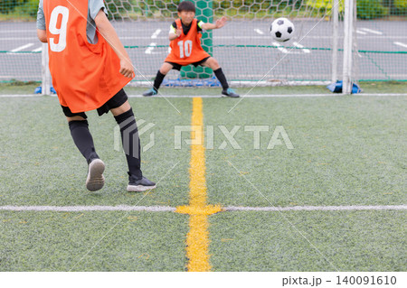 サッカーでシュートをする少年選手とゴールキーパー 140091610