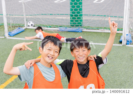 サッカーでゴールを決め笑顔で肩を組む少年たち 140091612