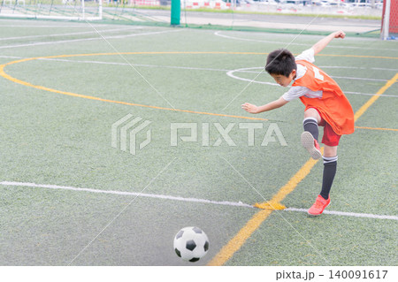 サッカーでシュートを打つ少年 140091617